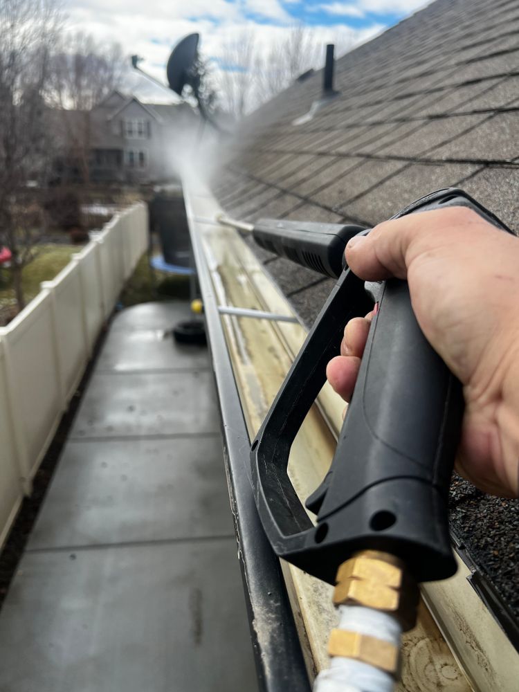 Residential roof gutter being cleared with professional cleaning equipment