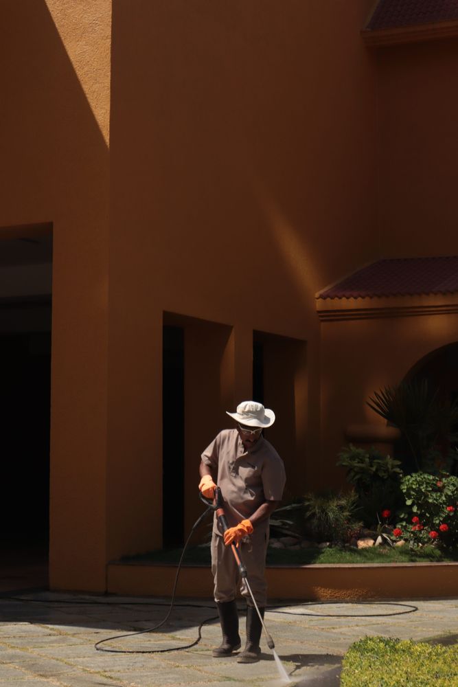 Worker pressure cleaning an outdoor paved surface